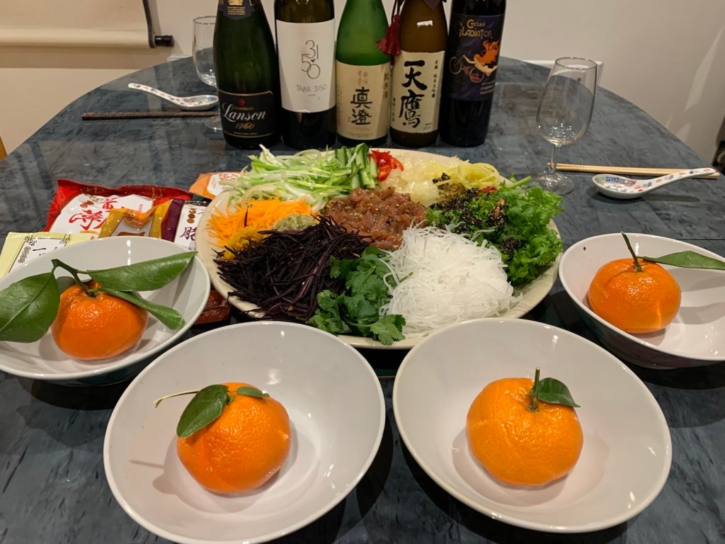 Image of Yee Sheng "Prosperity Toss Salad" with bottles of sake