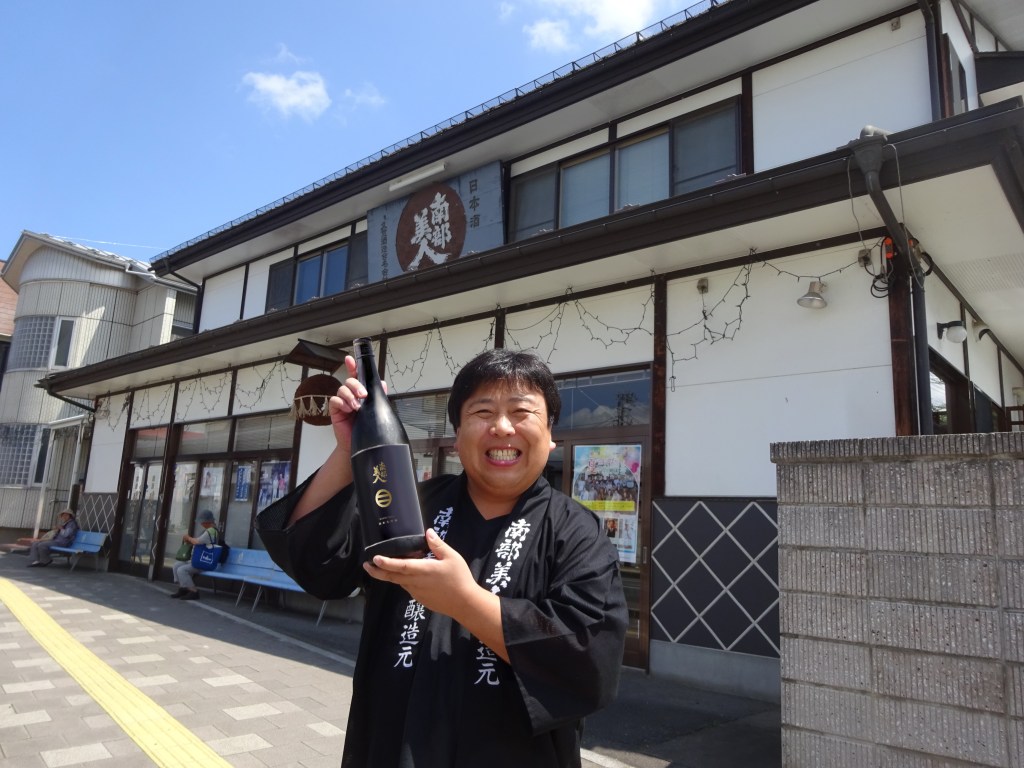 Mr. Kosuke Kuji holding a bottle of Nanbu Bijin in front of the brewery